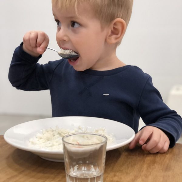 Niño comiendo con cuchara en plato.